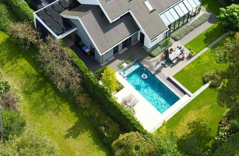 Aerial view of a designer pool and detached house set in a well tended garden