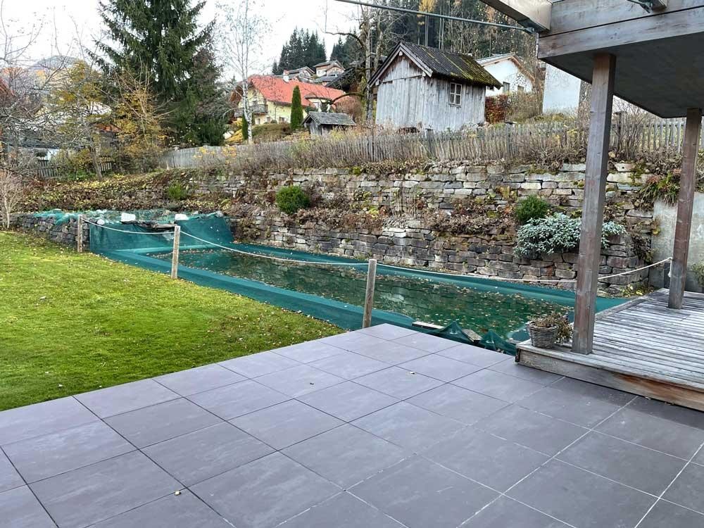 Biopool in autumn with protective net, terrace and natural stone wall