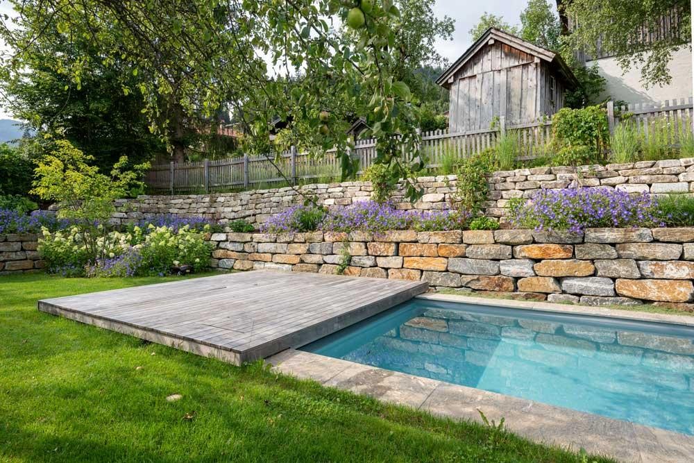 Biopool with wooden deck, natural stone wall and flowering plants