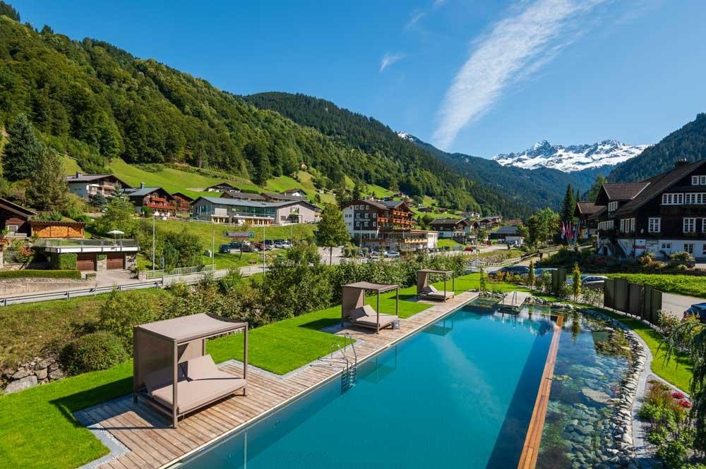 Aerial view of a hotel pool in an alpine village with mountain scenery
