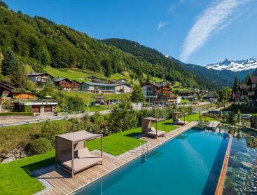 Aerial view of a hotel pool in an alpine village with mountain scenery