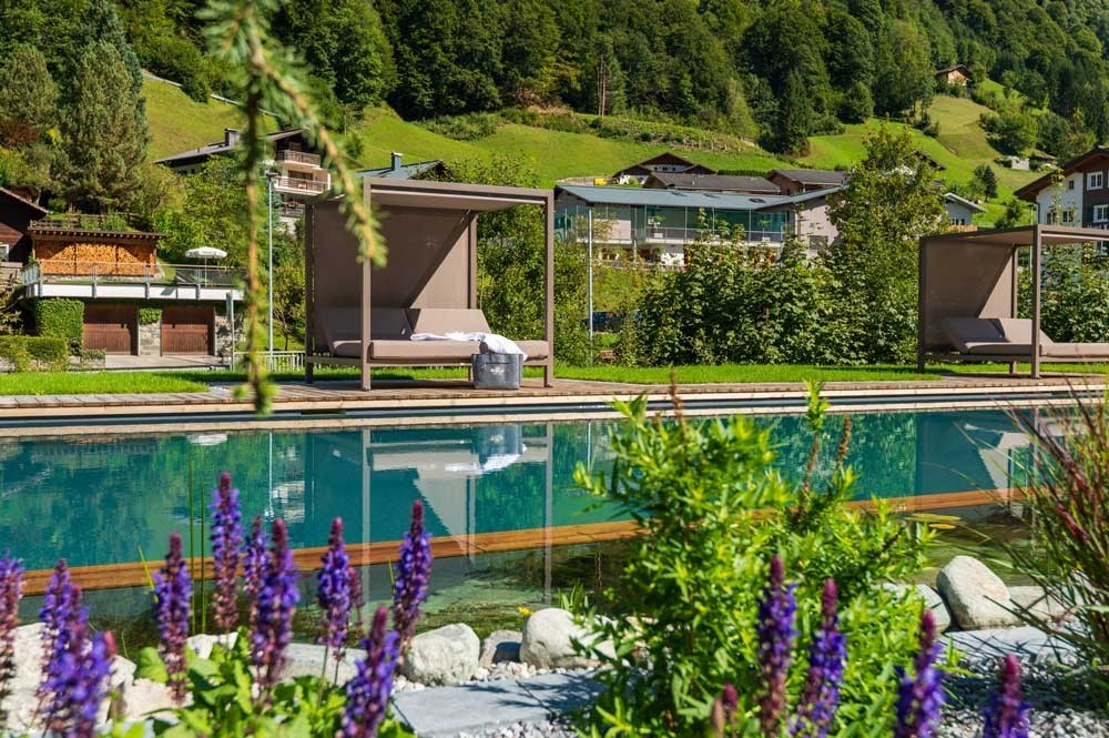 Hotel pool with daybeds and alpine panorama in a green setting