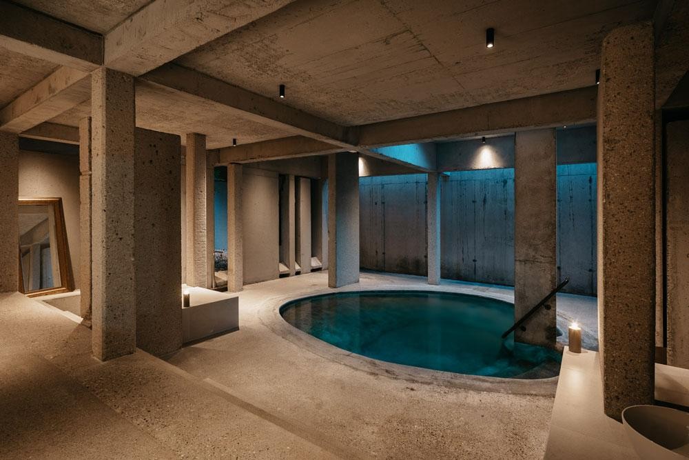 Round indoor pool with concrete architecture and atmospheric lighting