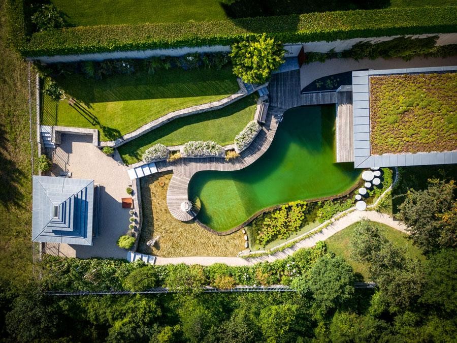 Biotop natural pool from above with wooden deck green roof and garden