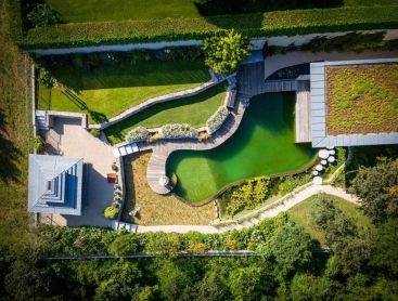 Biotop natural pool from above with wooden deck green roof and garden