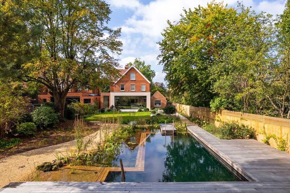Natural pool with wooden deck and garden house in a nature-inspired garden