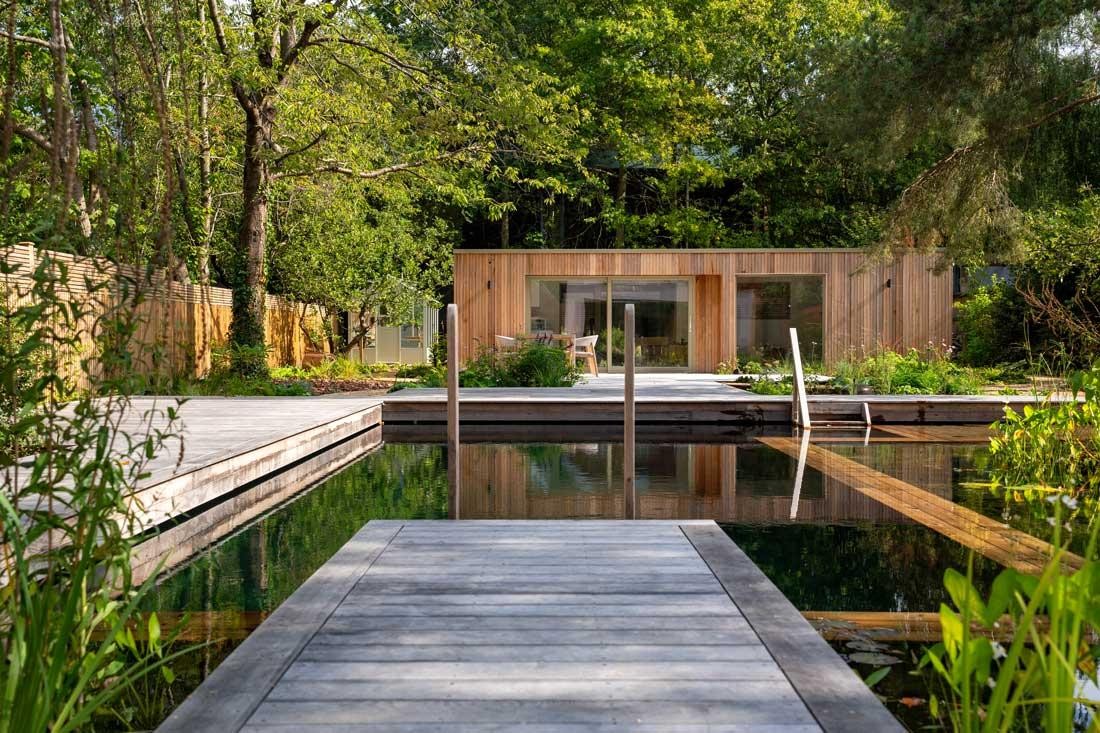 Natural pool with regeneration zone and wooden walkway in a nature-inspired garden