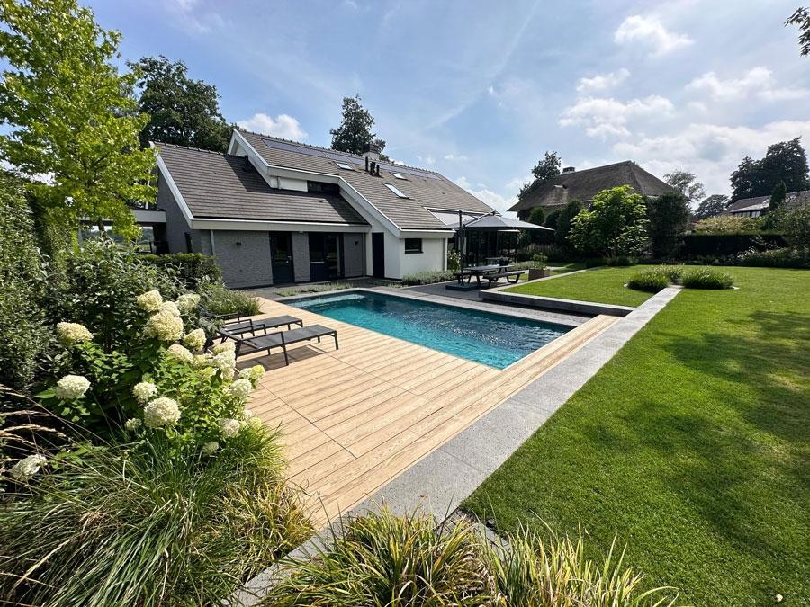 Designer pool with a wooden terrace in a well kept family garden