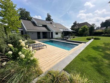 Designer pool with a wooden terrace in a well kept family garden