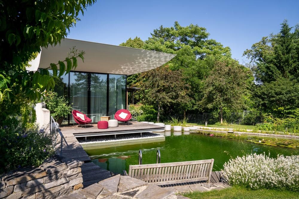 Biotop swimming pond by modern terrace with wooden deck and seating area