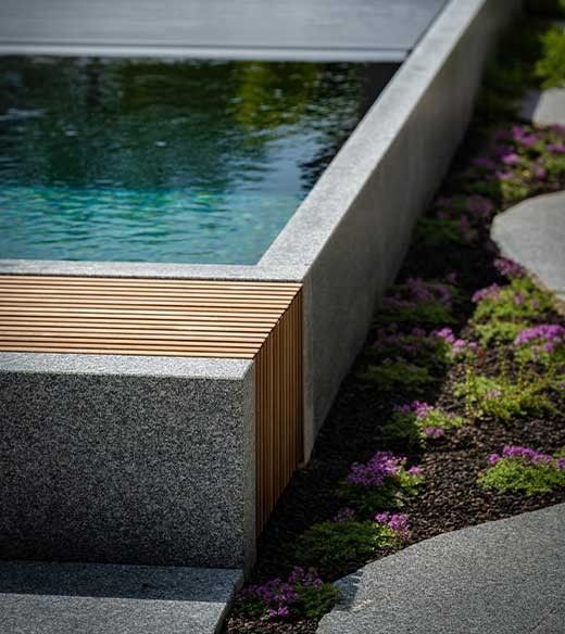 Detail of natural granite pool with pool cover and wooden elements