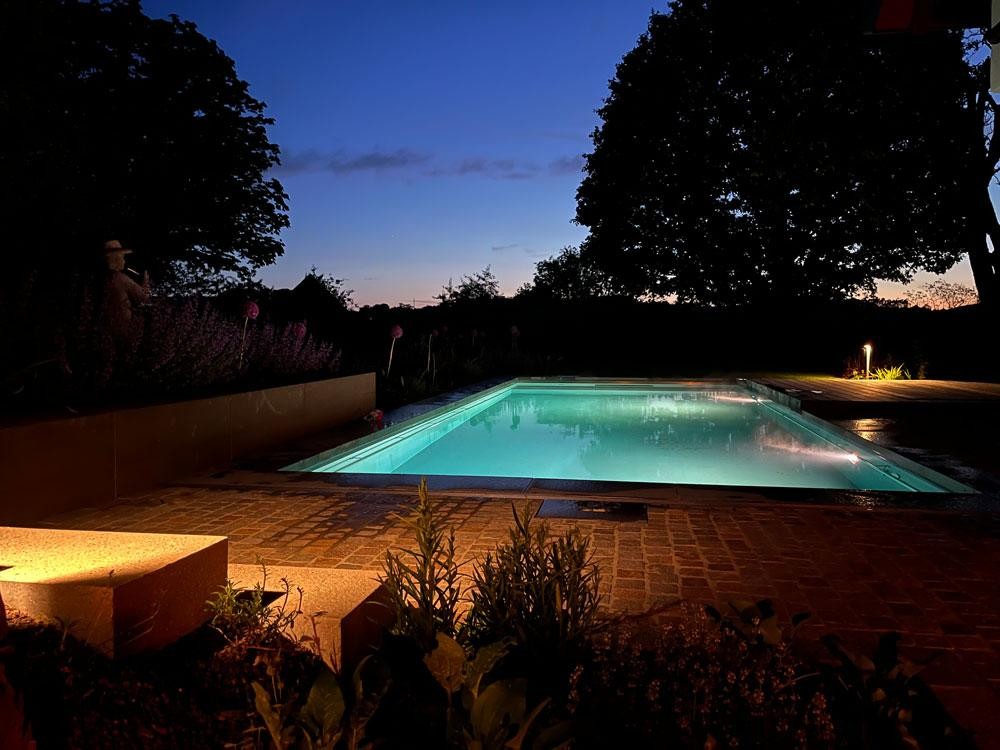 Illuminated natural pool in the evening with garden atmosphere