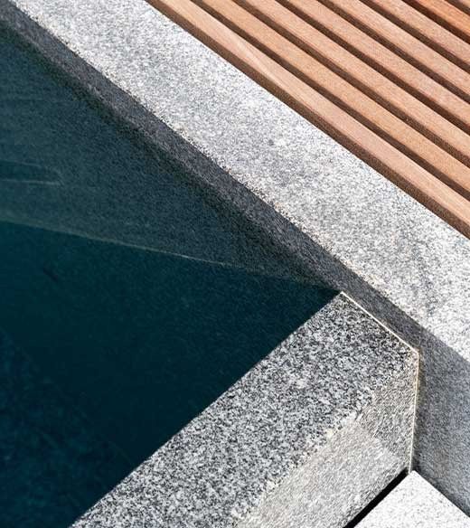 Close up of grey granite of a Kusser pool with adjoining wooden terrace