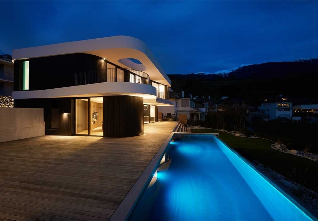 Modern architecture with illuminated natural pool at night in Italy