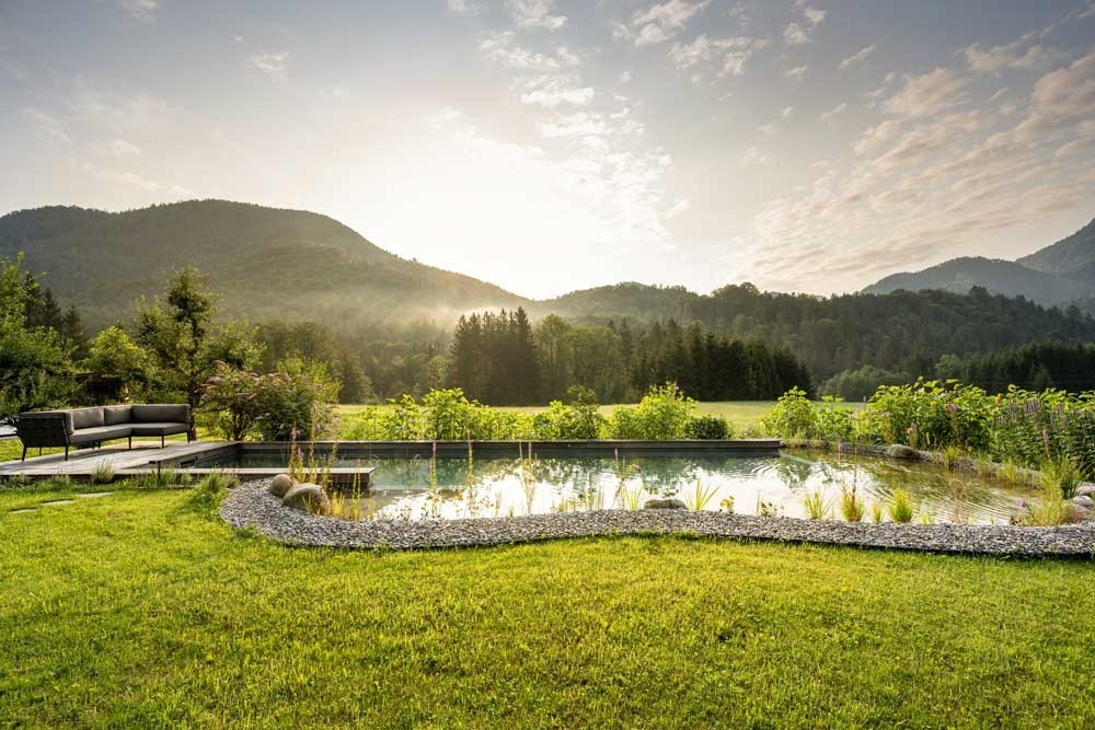 Biotop natural pool in an idyllic garden landscape at sunrise surrounded by mountains