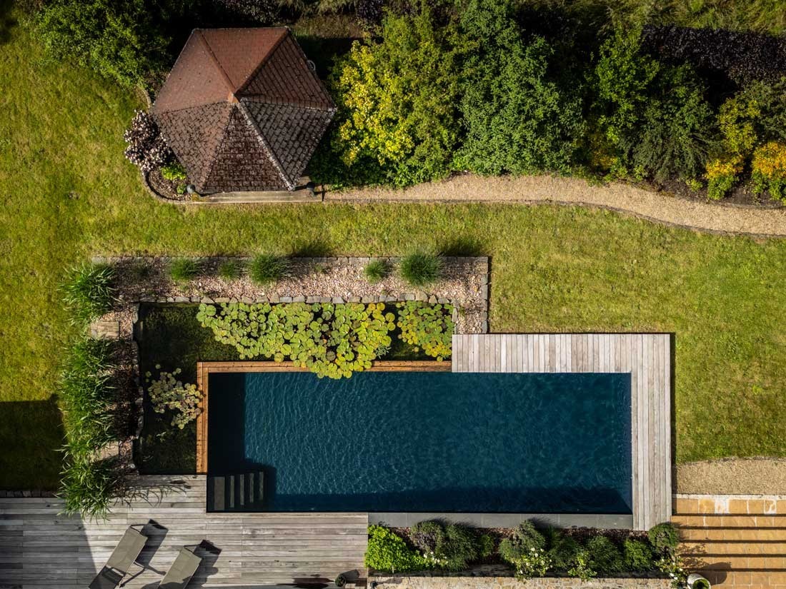 Natural swimming pond with wooden deck in a spacious garden