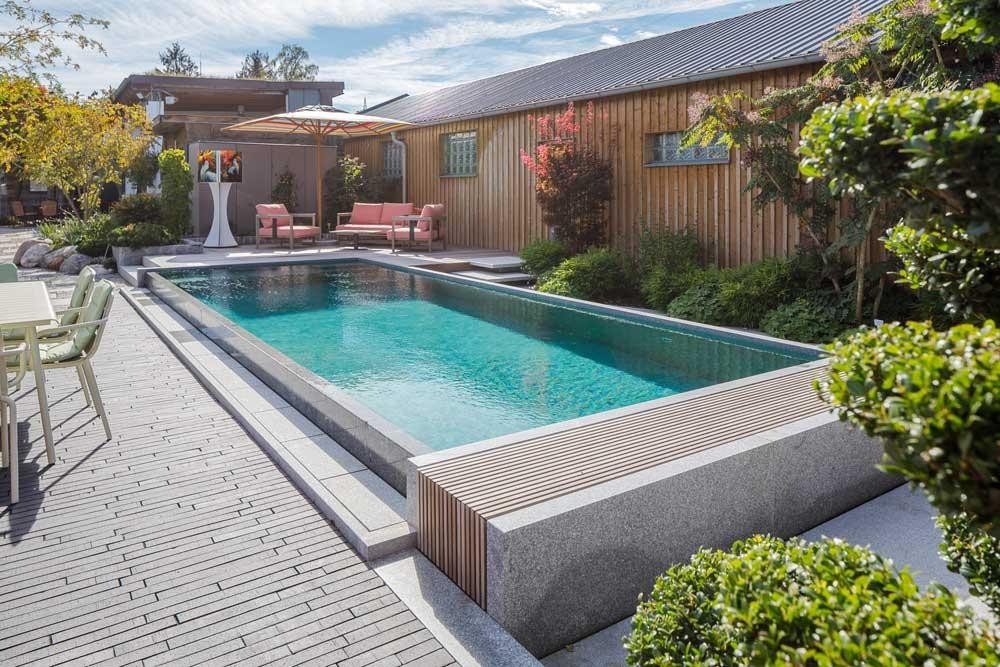 Modern BIOTOP natural pool in the garden with wooden deck and seating area