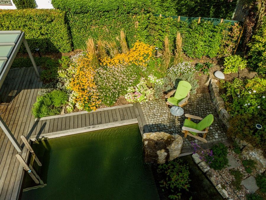 Seating area by swimming pond with flower bed and green chairs